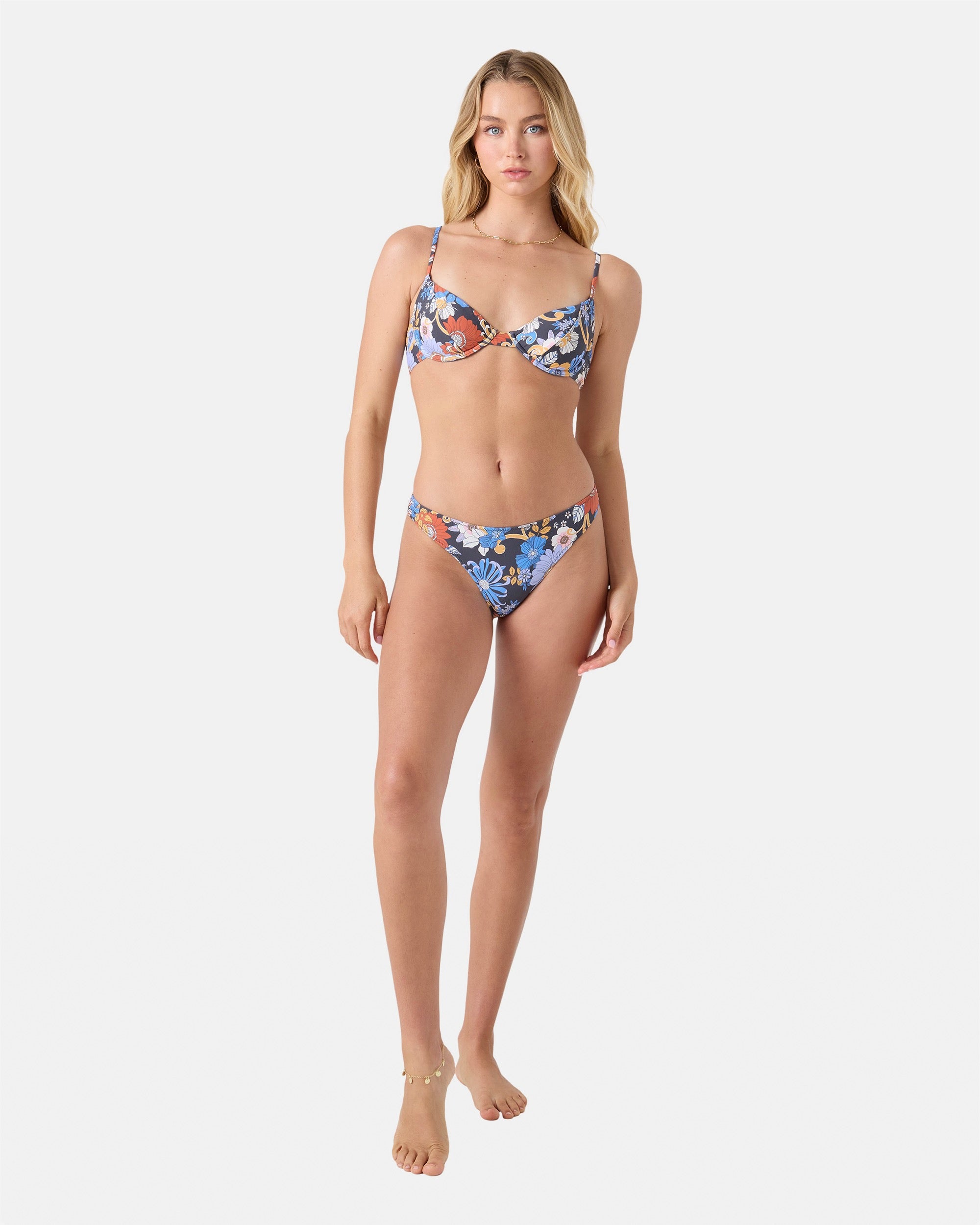 A woman barefoot and neutral-faced poses against a white background wearing the Roxy®一分钟极速赛车168开奖结果记录体彩历史号码查询 Soul Flower Smocked Demi Underwire Bikini Top in Gray Combo with matching recycled nylon bottoms, looking directly at the camera.